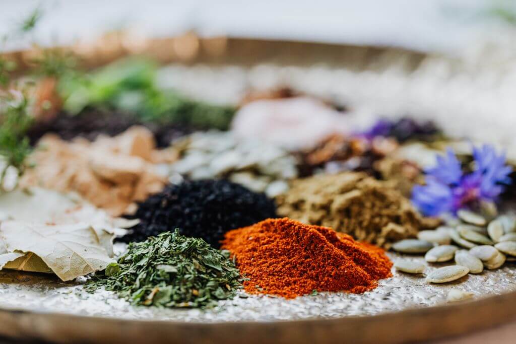 Close-up of colorful spices and herbs on a tray, showcasing a vibrant palette.